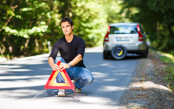 man putting emergency sign on roadside