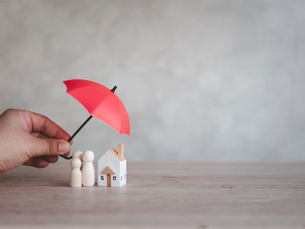 An umbrella over small figures that represent a family and their home