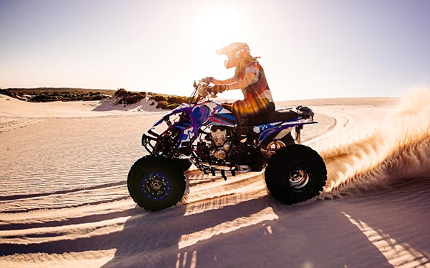 A person riding a blue ATV in the desert 