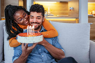 Two people celebrating someone's birthday with a cake and candles